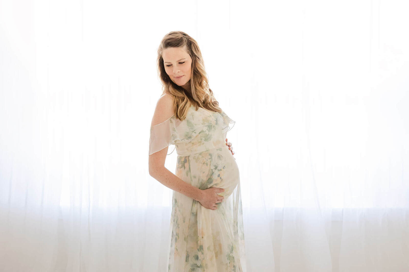 maternity photographer Birmingham Al mom in ethereal dress in front of light filled window