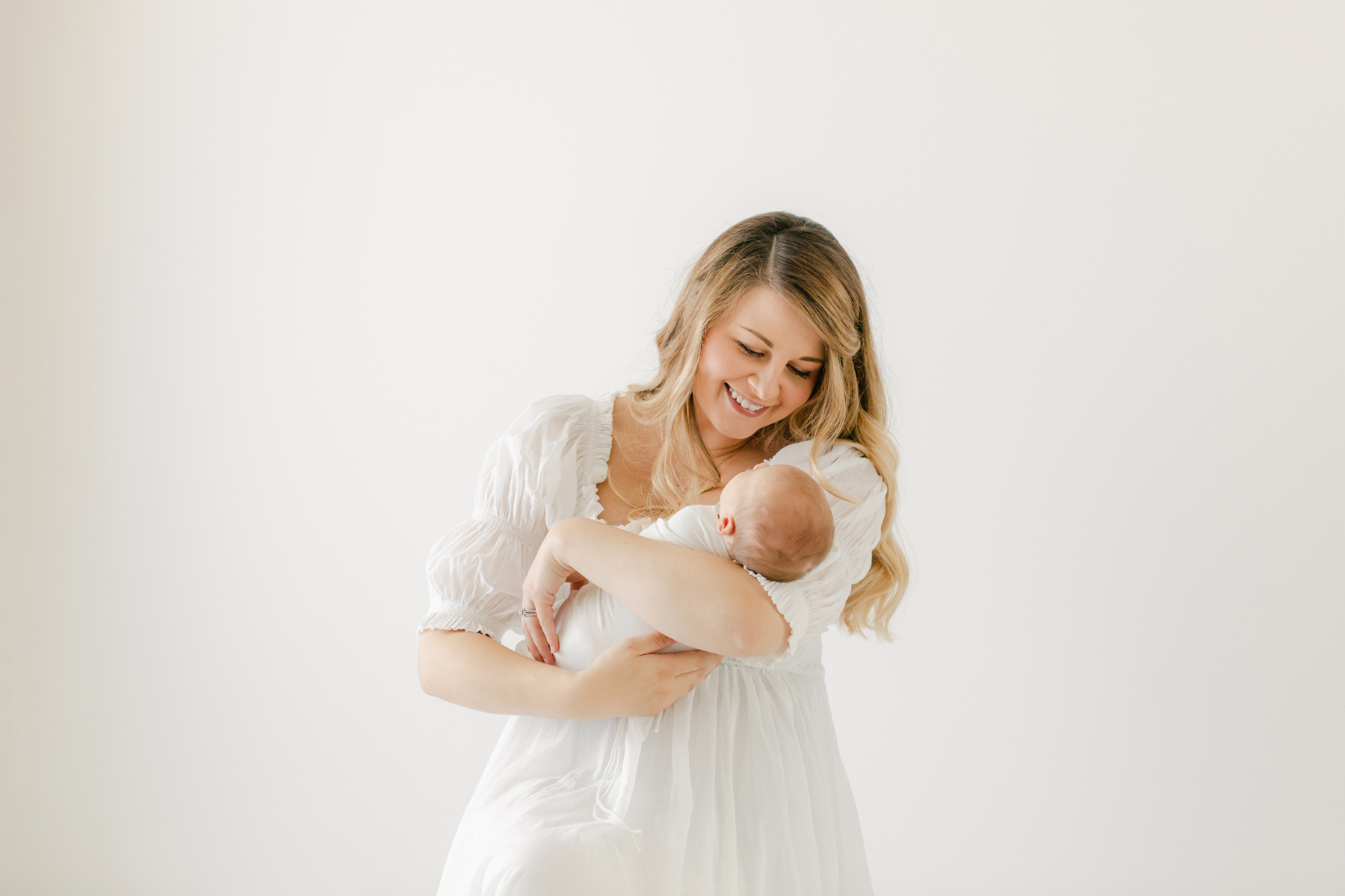 image of mom cuddling baby in white dress by montgomery newborn photographer Virginia Schultz