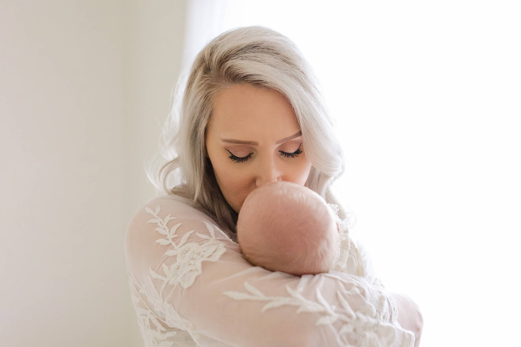 image of postpartum mom kissing baby with gorgeous glowing skin from a trip to one of the spas in tuscaloosa