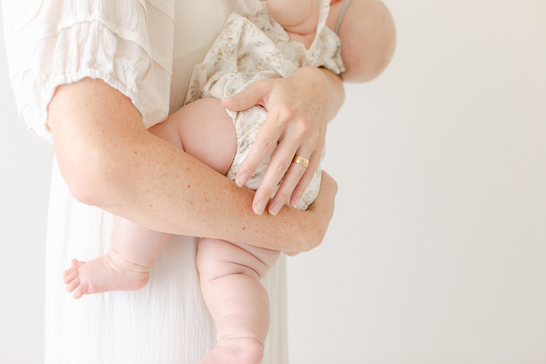 Mother cradling her 3 month old baby in an all white studio for prenatal yoga birmingham al